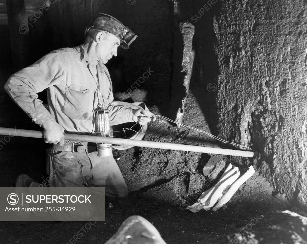Stock Photo: 255-34929 Side profile of a coal miner putting dynamite in to a hole