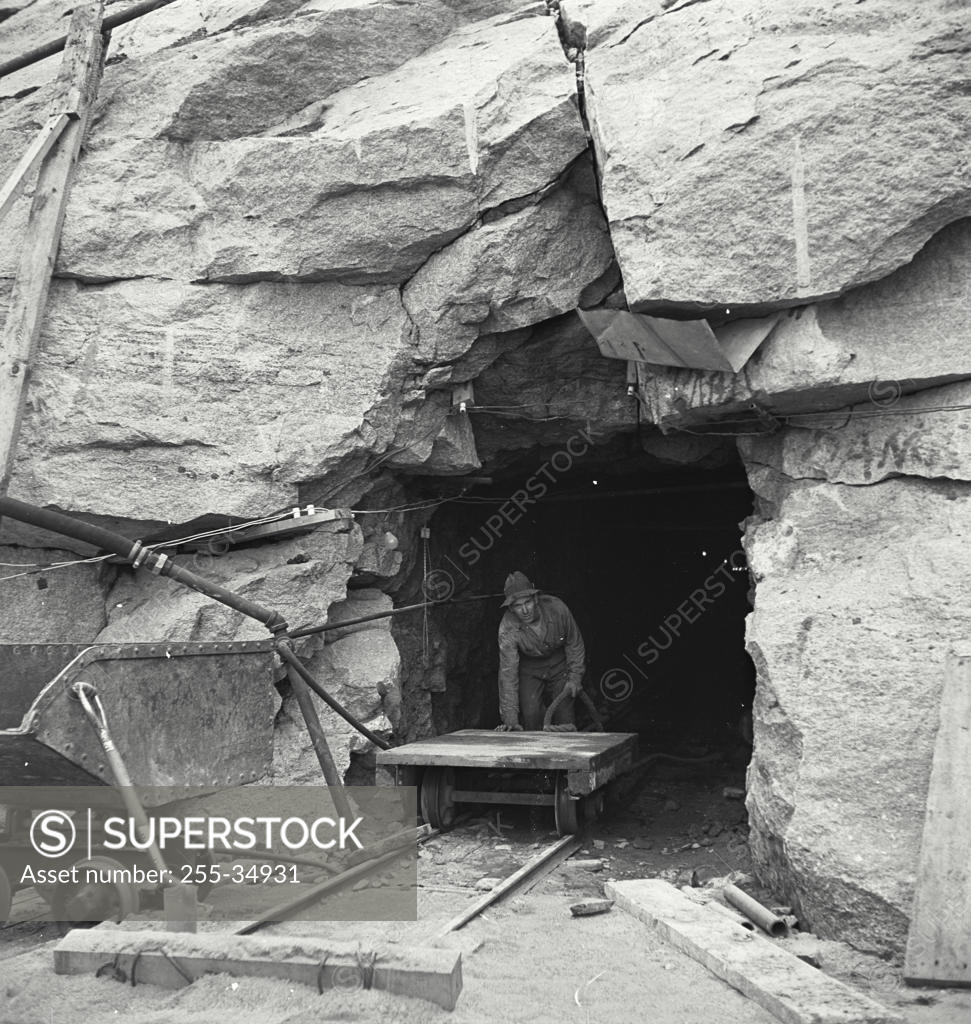 Stock Photo: 255-34931 Coal miner pushing a cart at the entrance of a pit mine