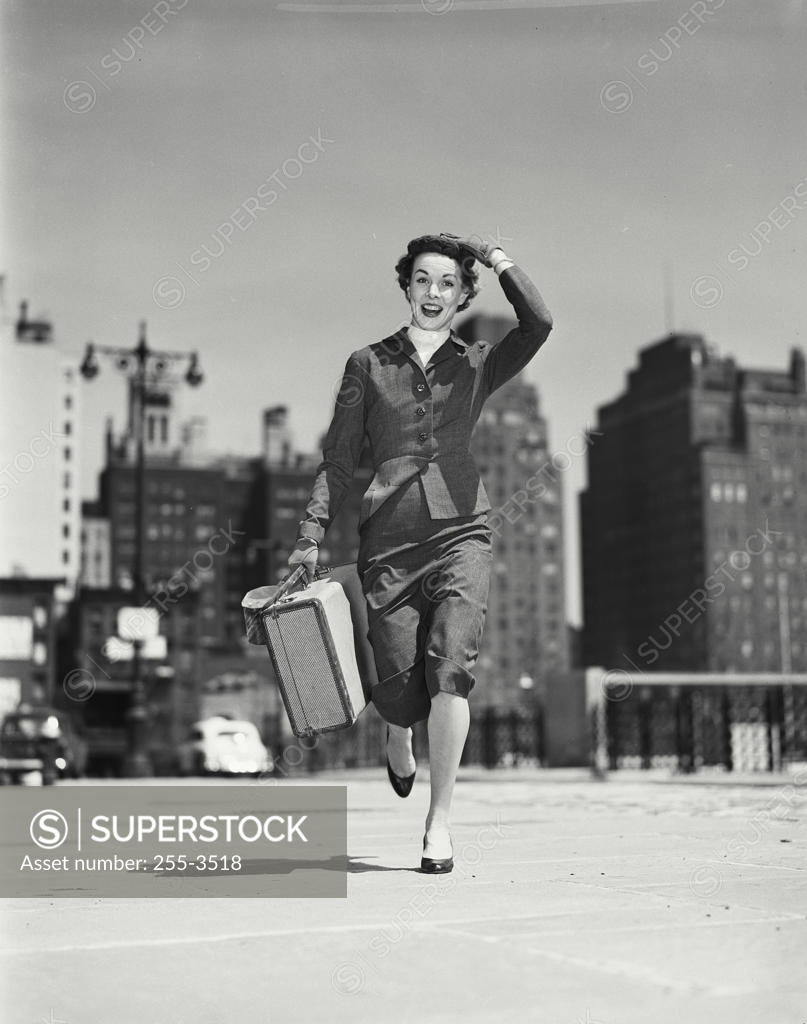 Stock Photo: 255-3518 Portrait of young woman carrying suitcase