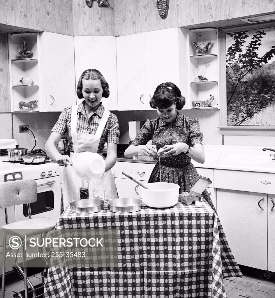 Stock Photo: 255-35483 Two teenage girls preparing food in the kitchen