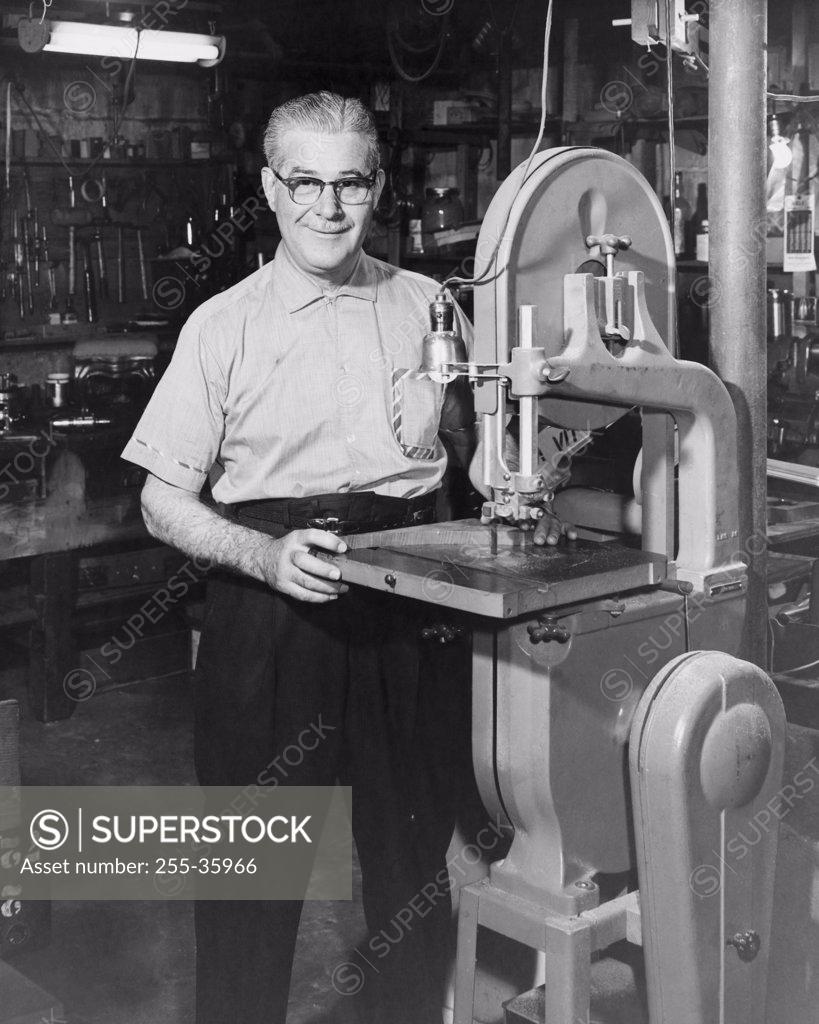 Stock Photo: 255-35966 Portrait of a senior man standing near a machine in a workshop