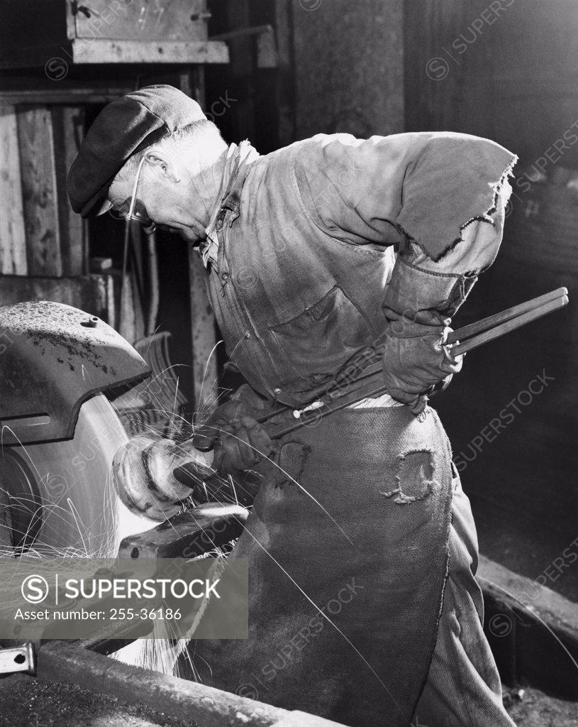 Stock Photo: 255-36186 Side profile of a senior man working on a machine in a factory