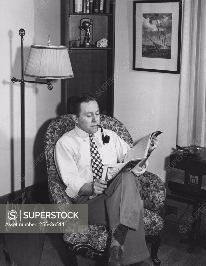 Stock Photo: 255-36511 Young man reading a magazine in an armchair