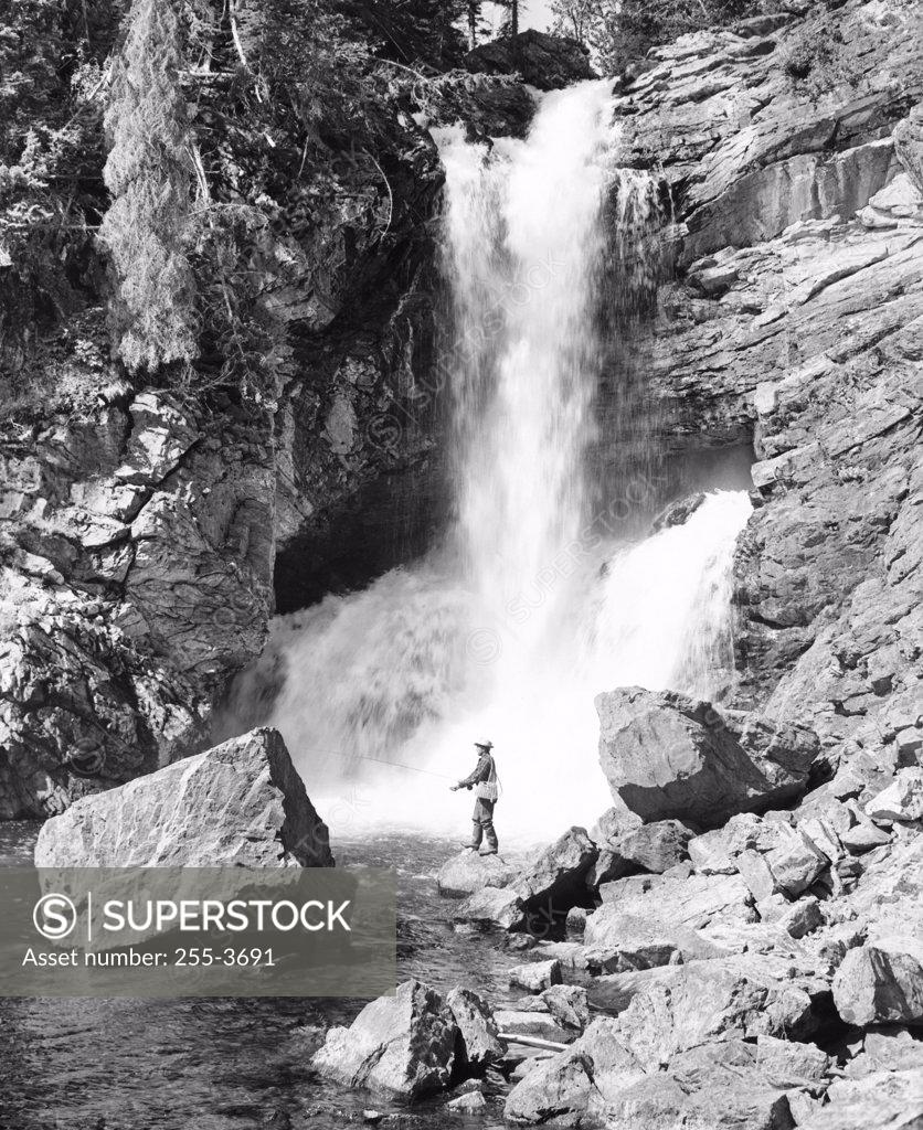Stock Photo: 255-3691 Man fly-fishing in front of a waterfall, Trick Falls, US Glacier National Park, Montana, USA