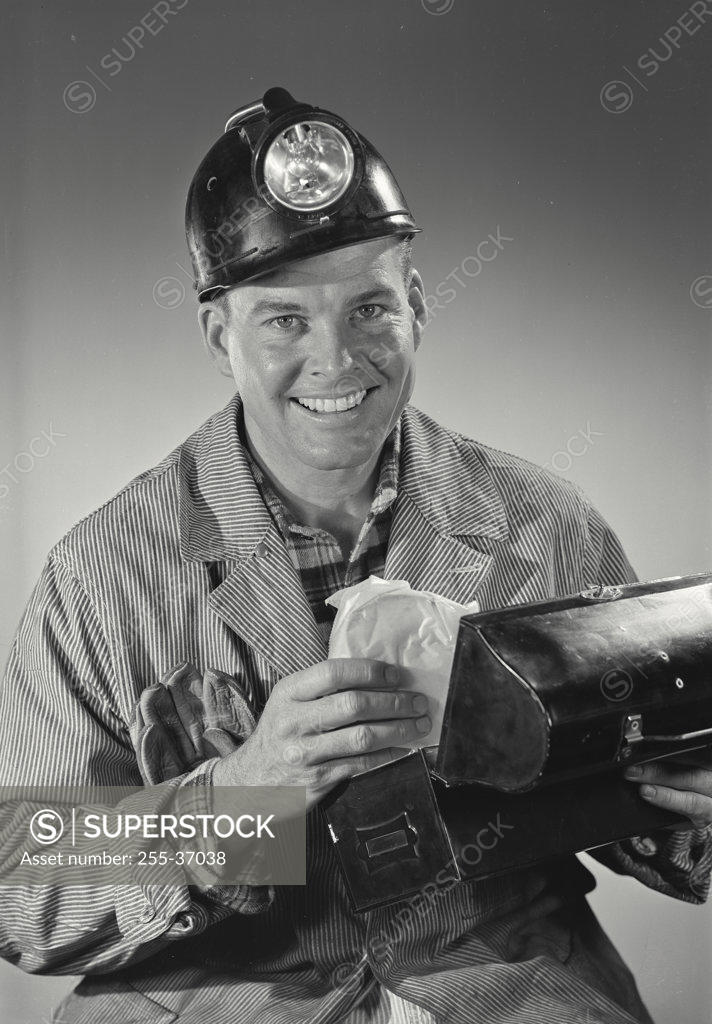Stock Photo: 255-37038 Portrait of a miner holding a lunch box and smiling