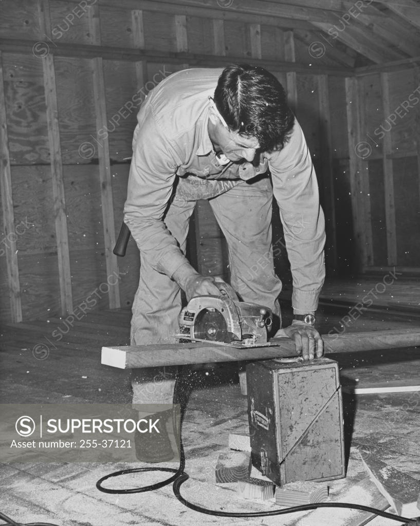 Stock Photo: 255-37121 Carpenter sawing a wooden plank using an electric saw