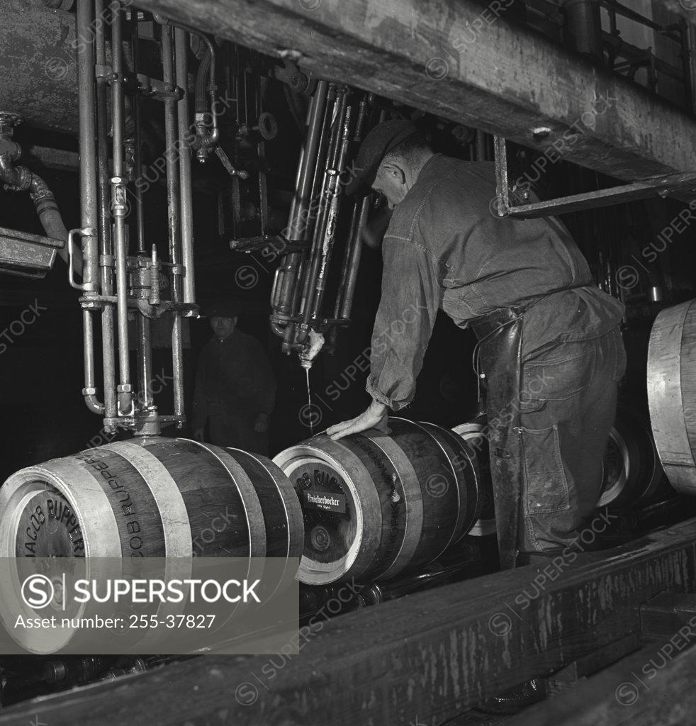 Stock Photo: 255-37827 Manual workers working on a machine in a distillery, Rupperts Brewery, New York City, New York State, USA