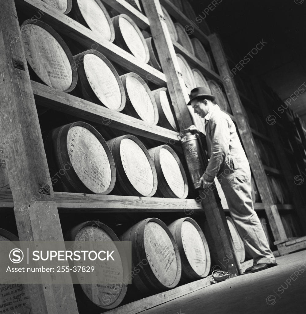 Stock Photo: 255-37829 Side profile of a male worker standing in front of barrels in a whisky storage room, Louisville, Kentucky, USA