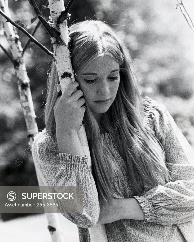 Stock Photo: 255-3895 Close-up of a teenage girl holding a tree trunk thinking