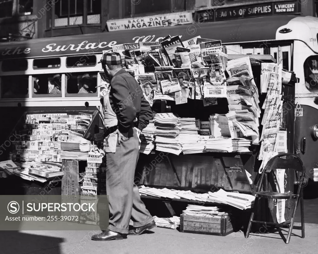 Side profile of a vendor standing in front of his news stand, New York City, USA