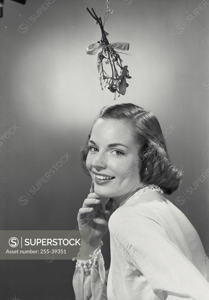 Stock Photo: 255-39351 Portrait of a young woman smiling with mistletoe hanging over her head
