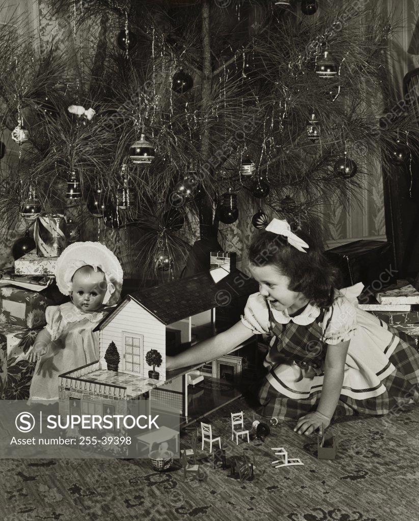 Stock Photo: 255-39398 Girl playing with a dollhouse near a Christmas tree