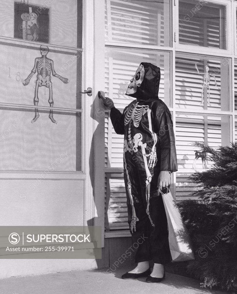 Stock Photo: 255-39971 Person wearing a Halloween costume pressing the doorbell of a house