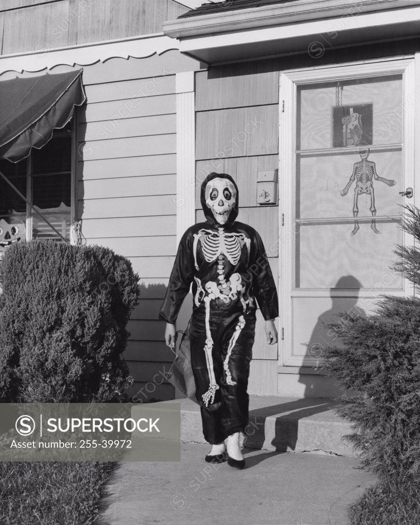 Stock Photo: 255-39972 Person wearing a Halloween costume walking on a footpath outside a house