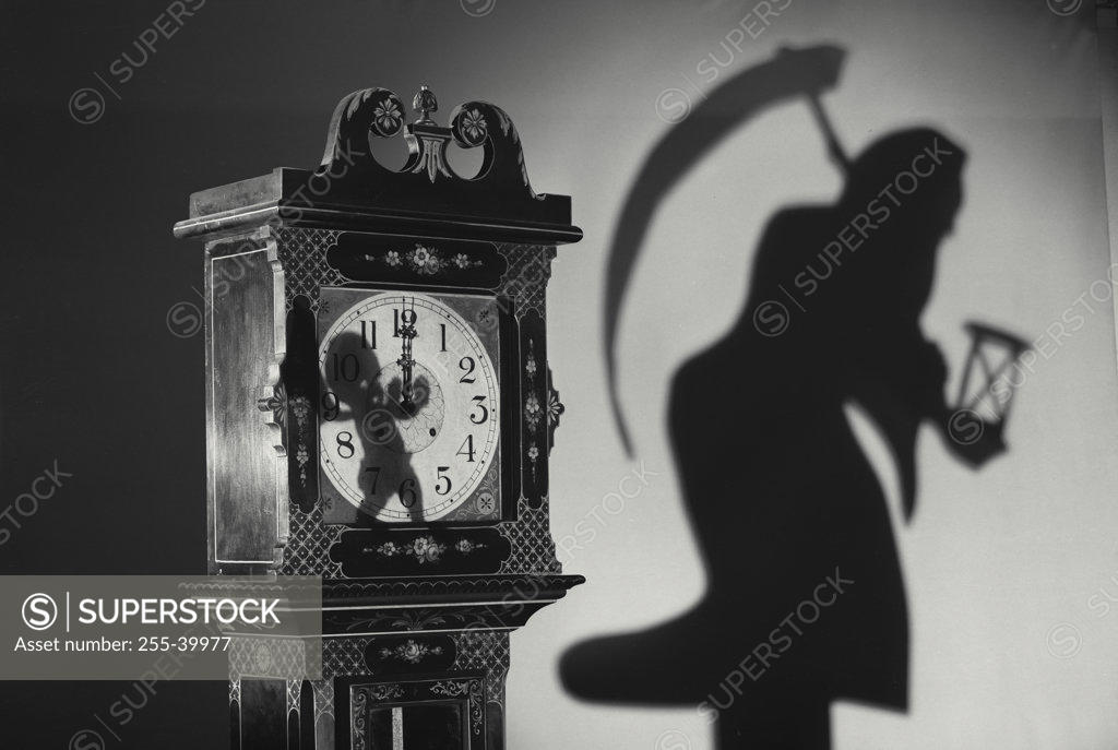 Stock Photo: 255-39977 Close-up of a clock with the shadow of a person carrying a scythe