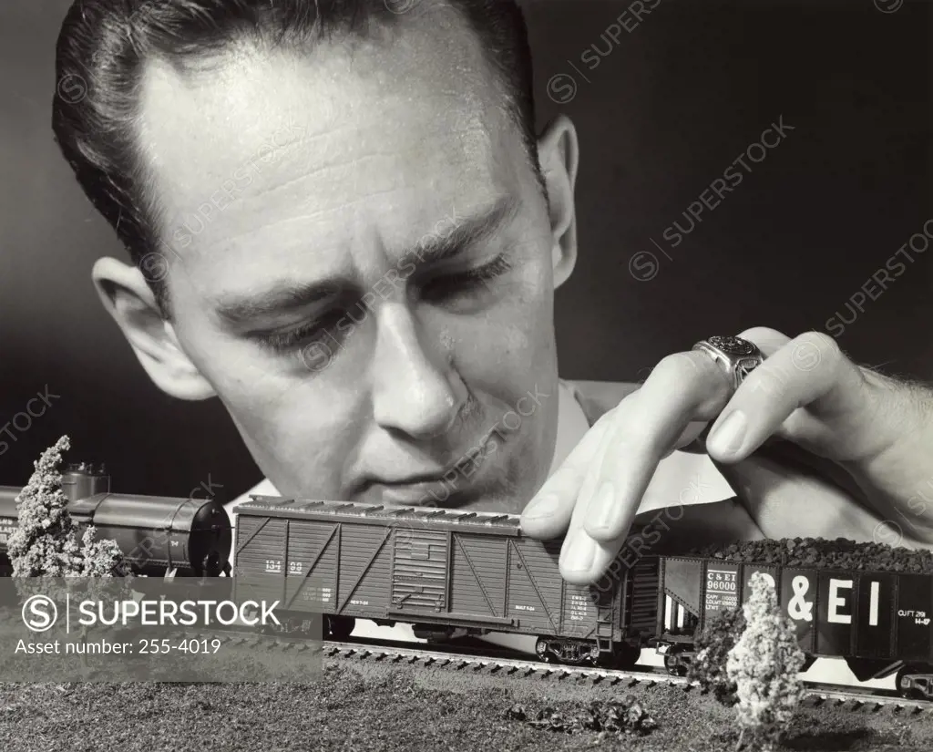 Close-up of a mid adult man holding a model of a toy train