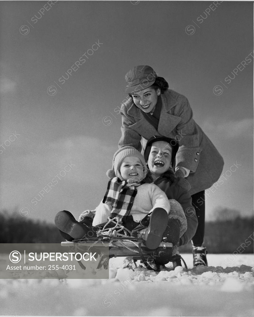 Stock Photo: 255-4031 Mother pushing her children on a sled