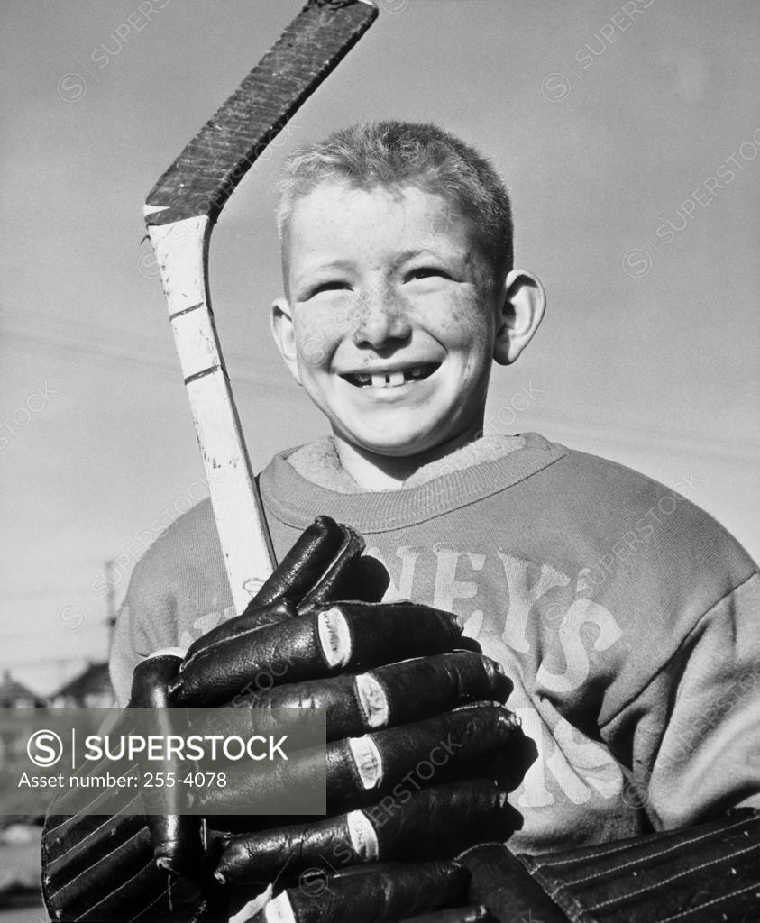 Stock Photo: 255-4078 Close-up of a boy holding a hockey stick smiling