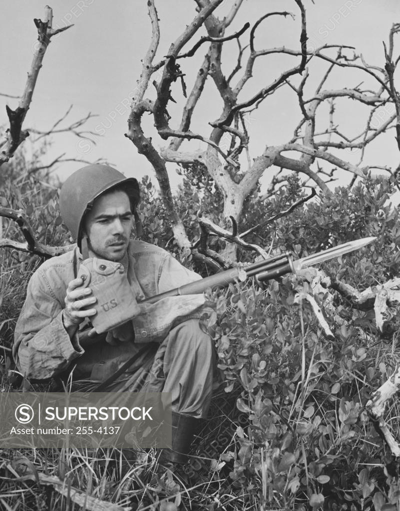 Stock Photo: 255-4137 Close-up of an army soldier holding a gun and a canteen