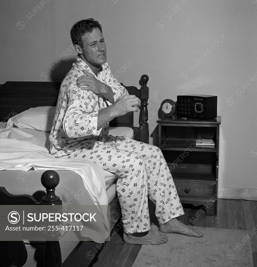 Stock Photo: 255-417117 Mid adult man getting up with painful facial expression
