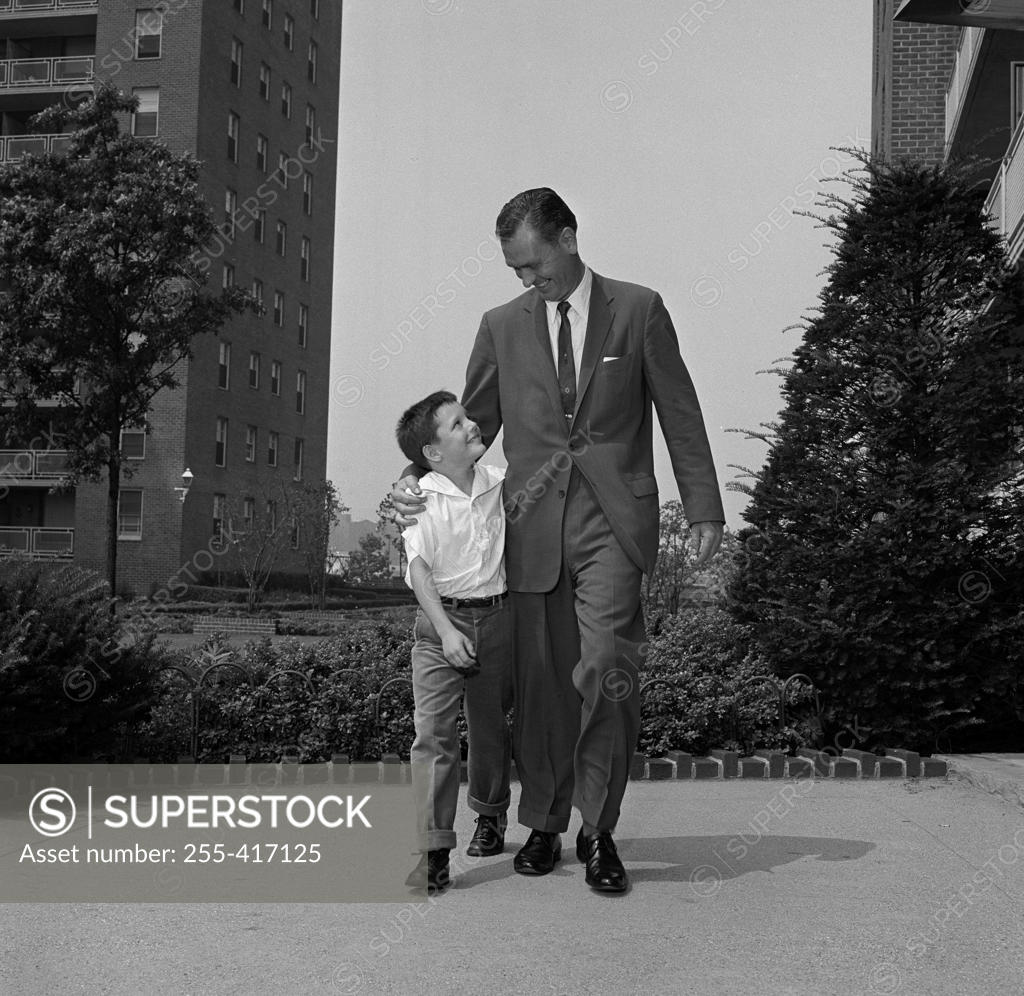 Stock Photo: 255-417125 Father walking with son with arm around him