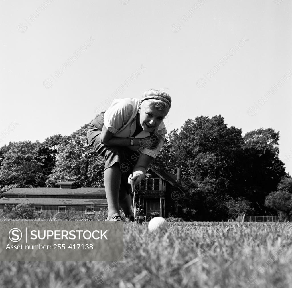 Stock Photo: 255-417138 Surface level view of young woman playing golf