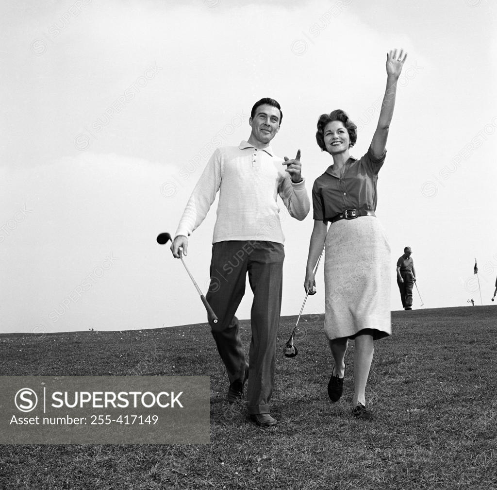 Stock Photo: 255-417149 Mid adult man and mid-adult woman walking in golf course