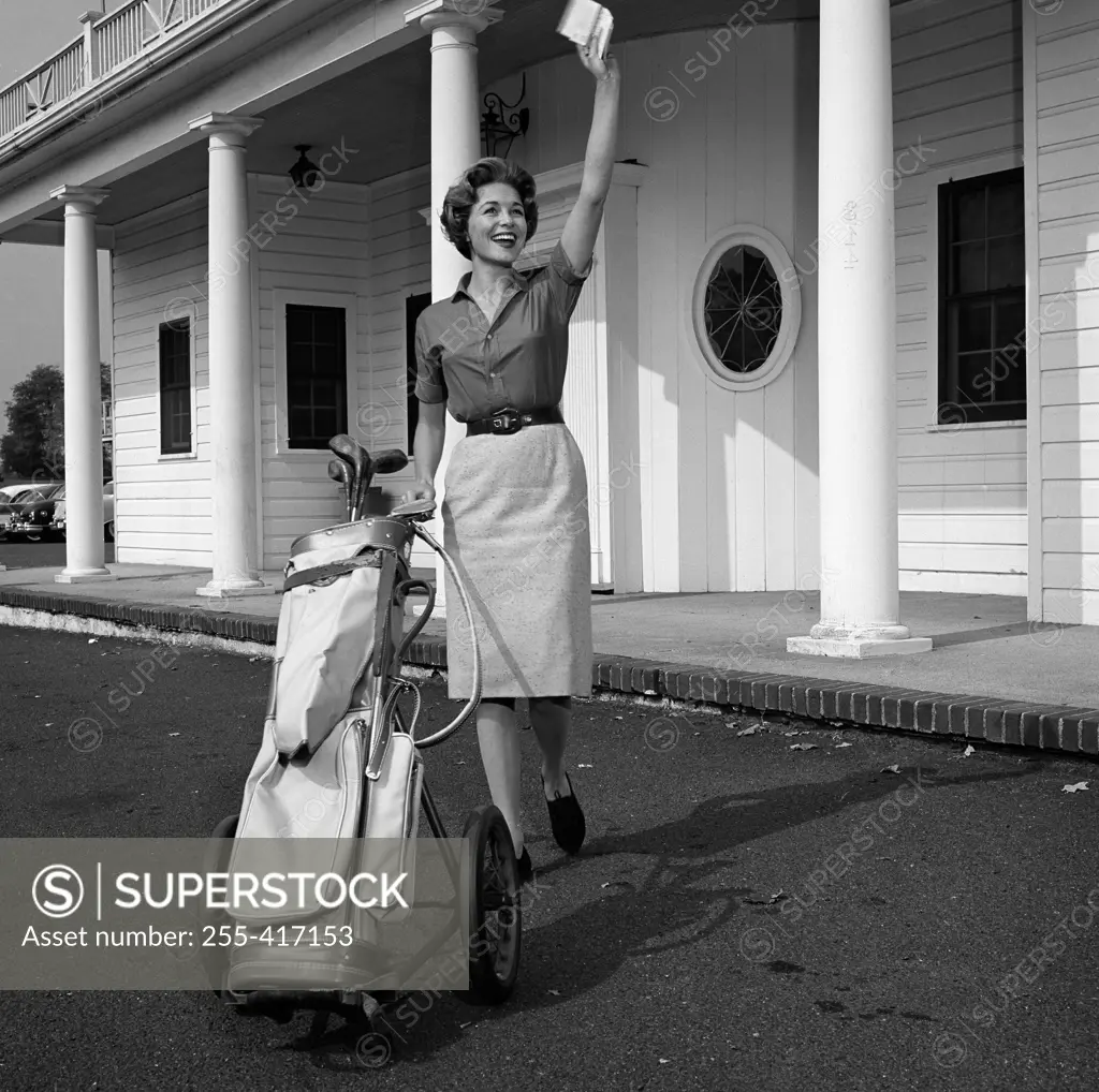Woman with gold bag, waving outside golf country club