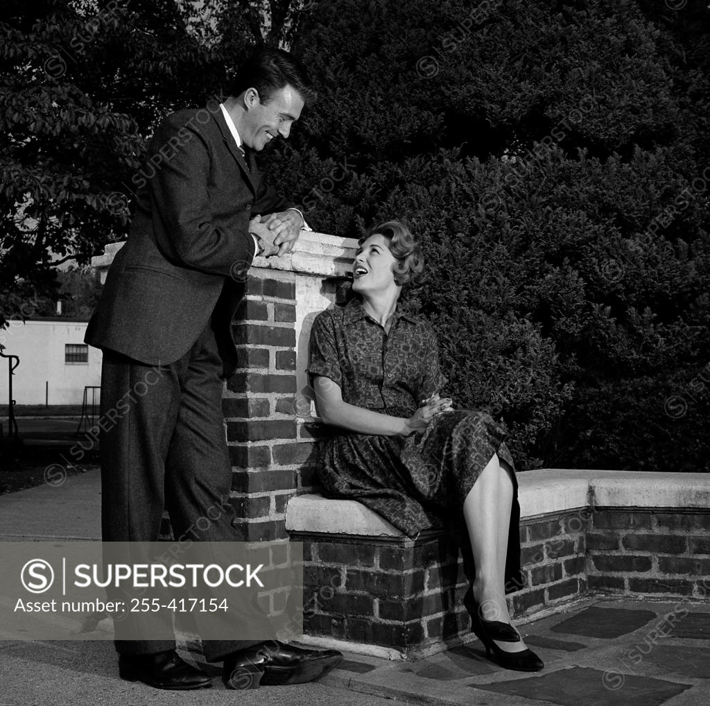 Stock Photo: 255-417154 Man talking to woman sitting on wall