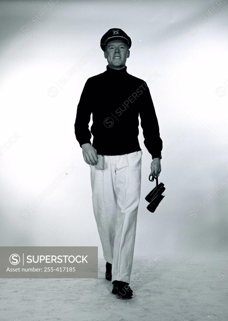Stock Photo: 255-417185 Studio portrait of man wearing sailor hat and carrying binoculars