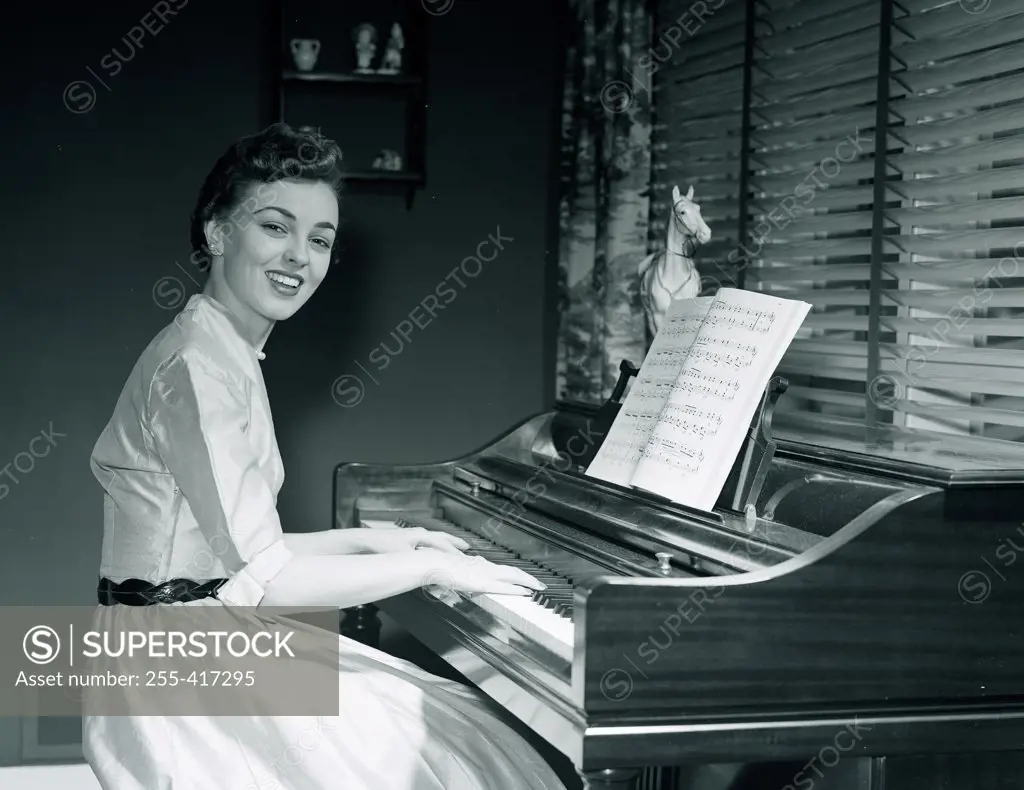 Portrait of young woman playing piano at home
