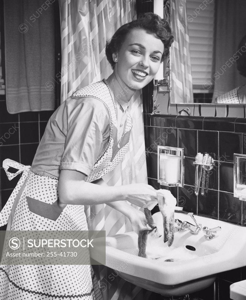 Stock Photo: 255-41730 Portrait of a young woman hand washing clothes in the bathroom sink.