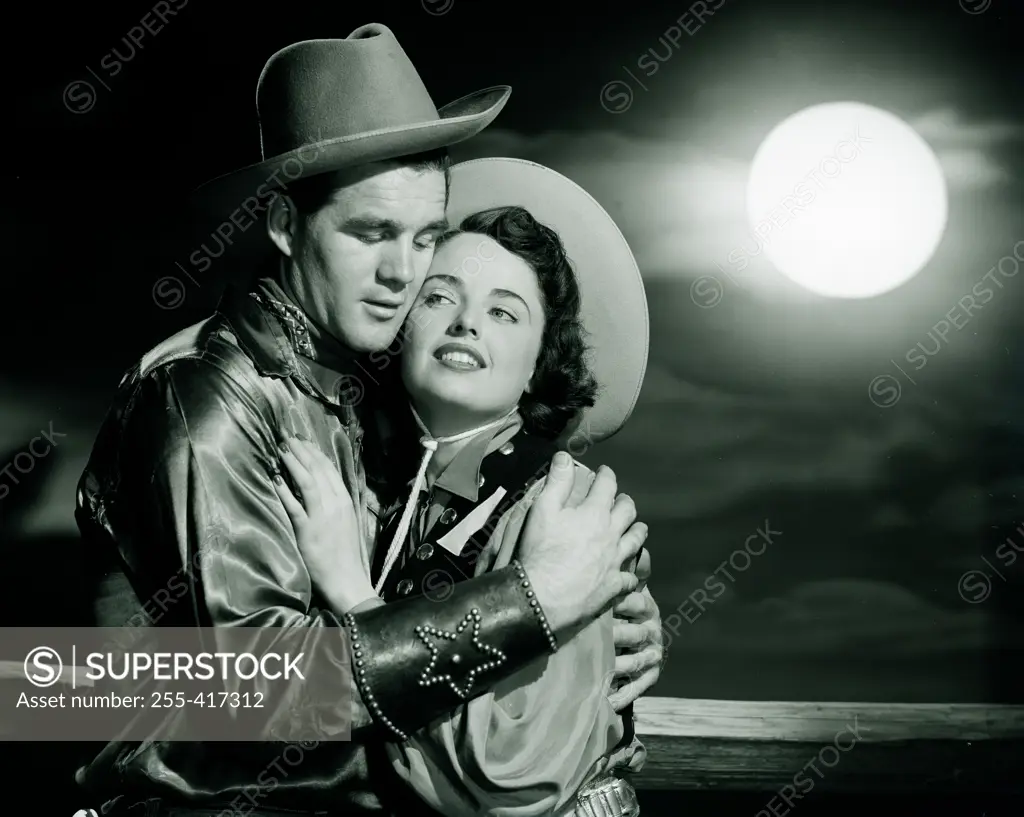 Cowboy embracing cowgirl at night