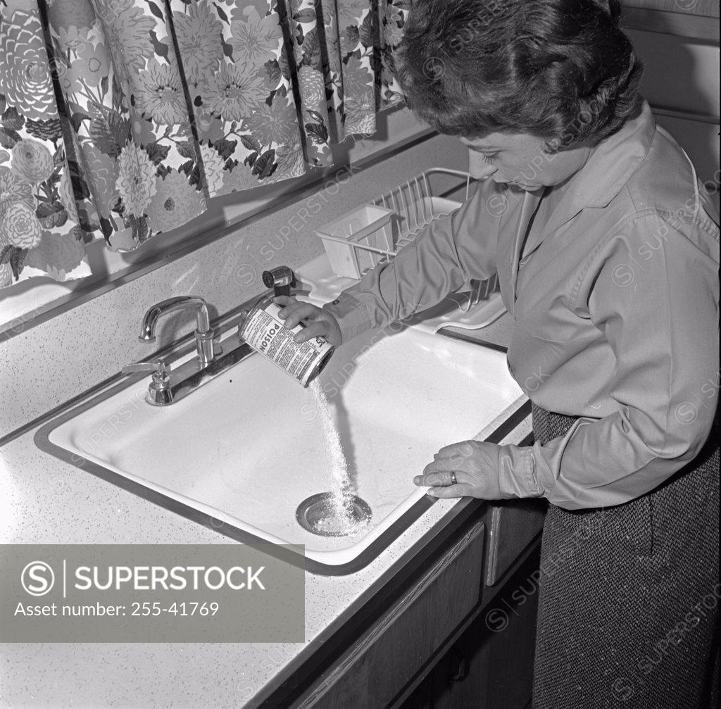Stock Photo: 255-41769 High angle view of a young woman pouring drain cleaner into a sink