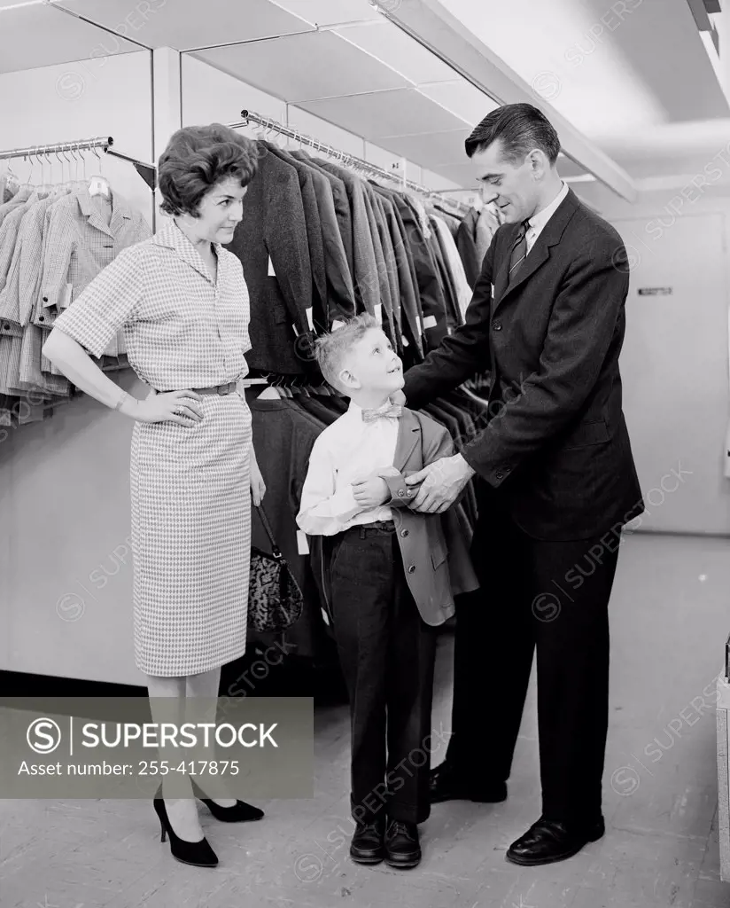 Parents assisting son trying on suit in shop