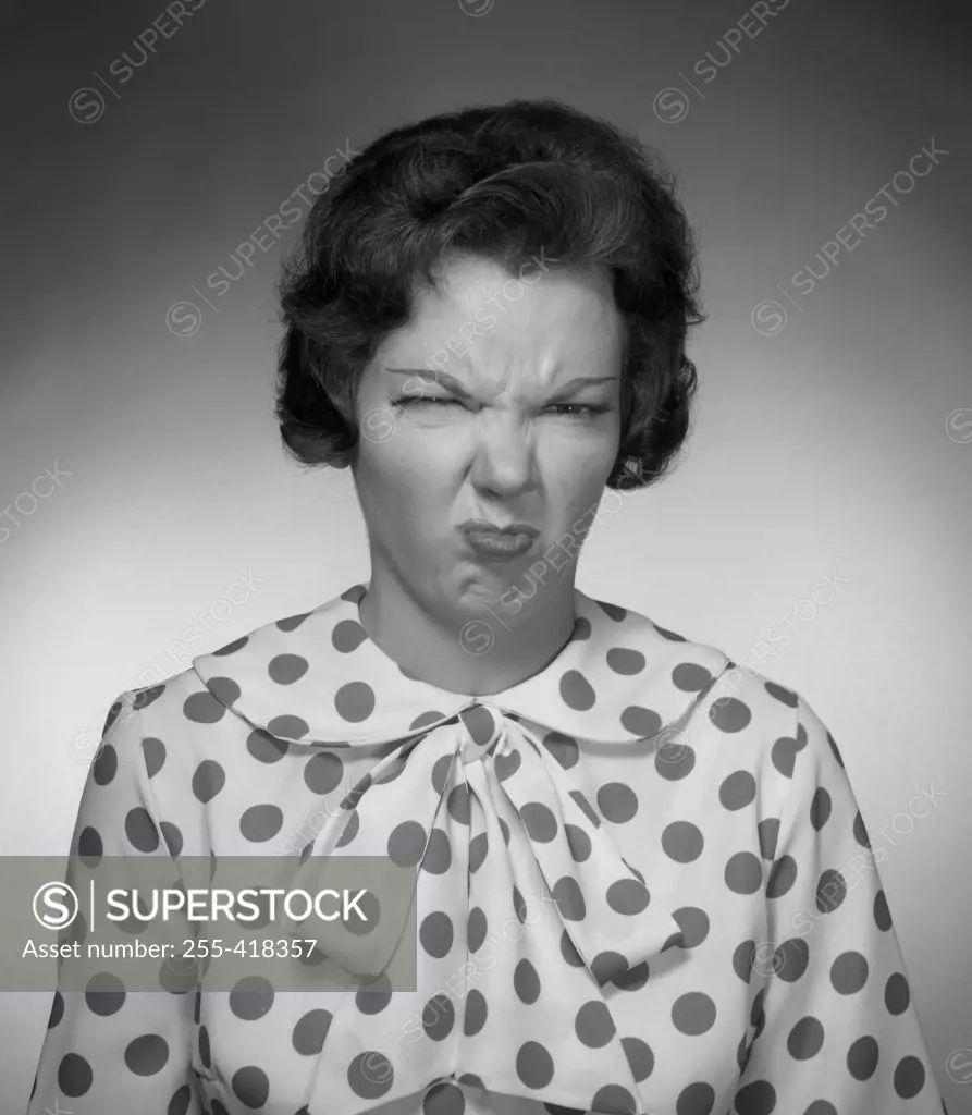 Woman in spotted blouse grimacing