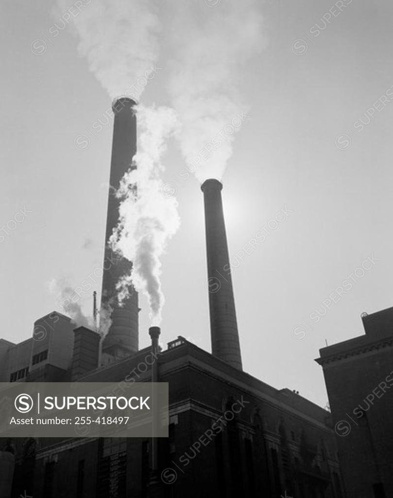 Stock Photo: 255-418497 Factory with smoking chimneys, low angle view
