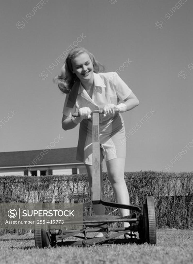 Stock Photo: 255-419773 Woman mowing lawn