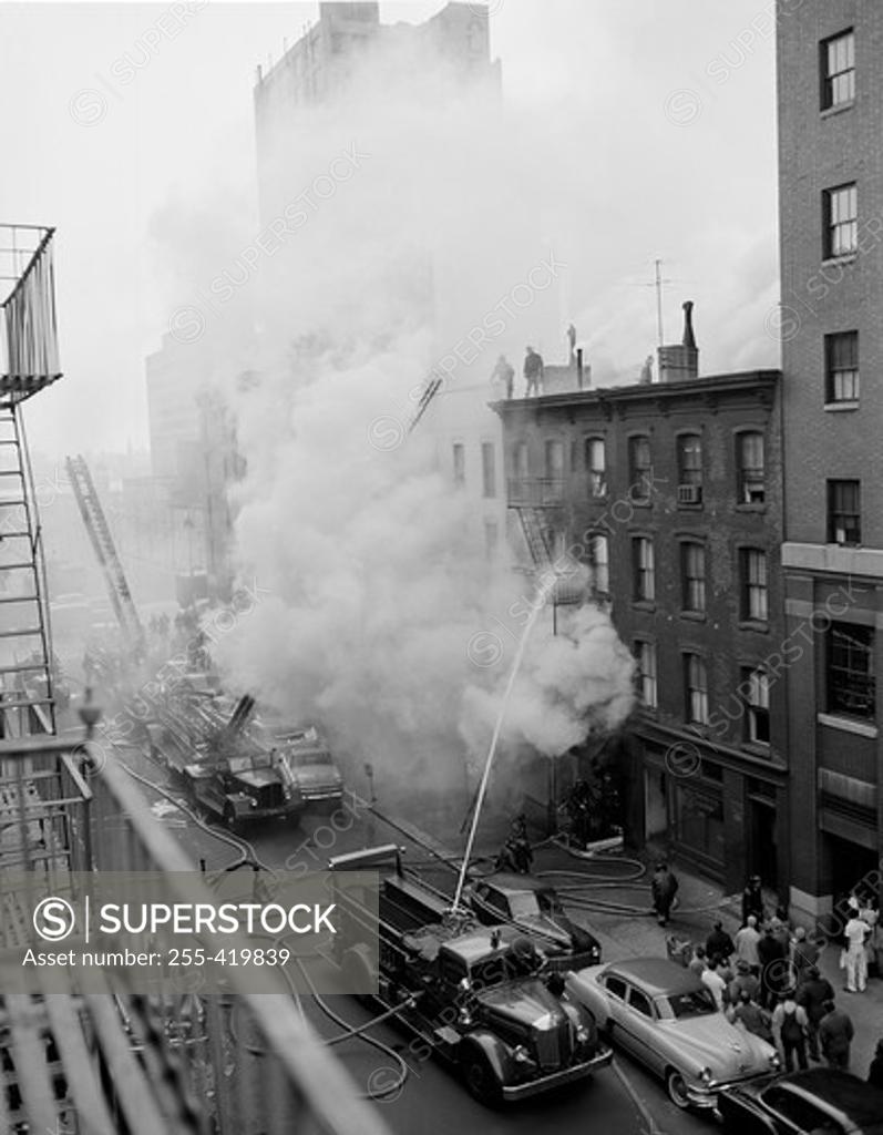Stock Photo: 255-419839 USA, New York State, New York City, Fire on East 47th Street, with fire engines shooting water on burning building