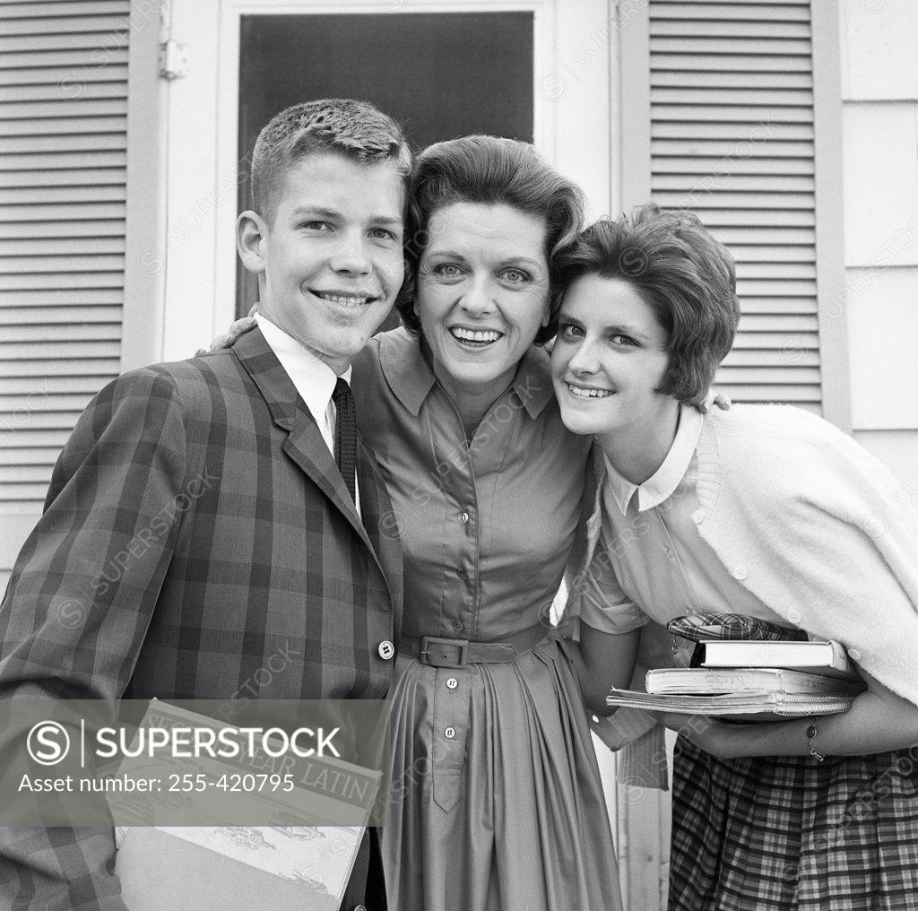 Stock Photo: 255-420795 Portrait of mother with teenage son and teenage daughter standing outside house