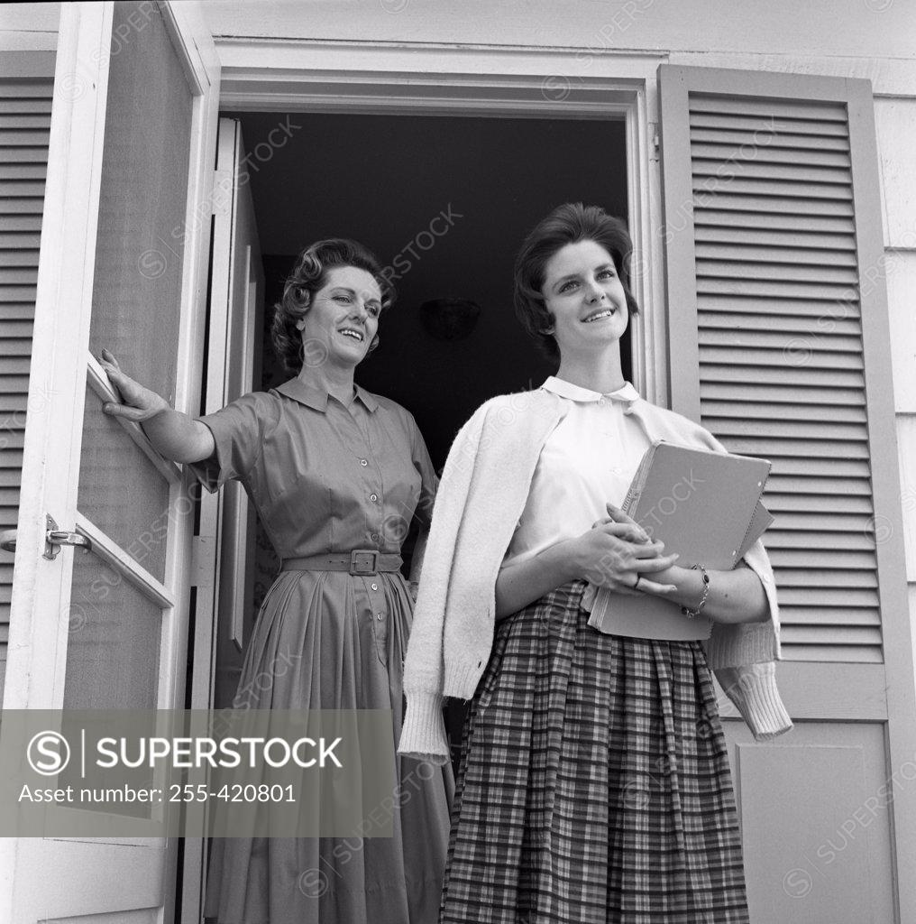 Stock Photo: 255-420801 Mother and teenage daughter standing in front of house