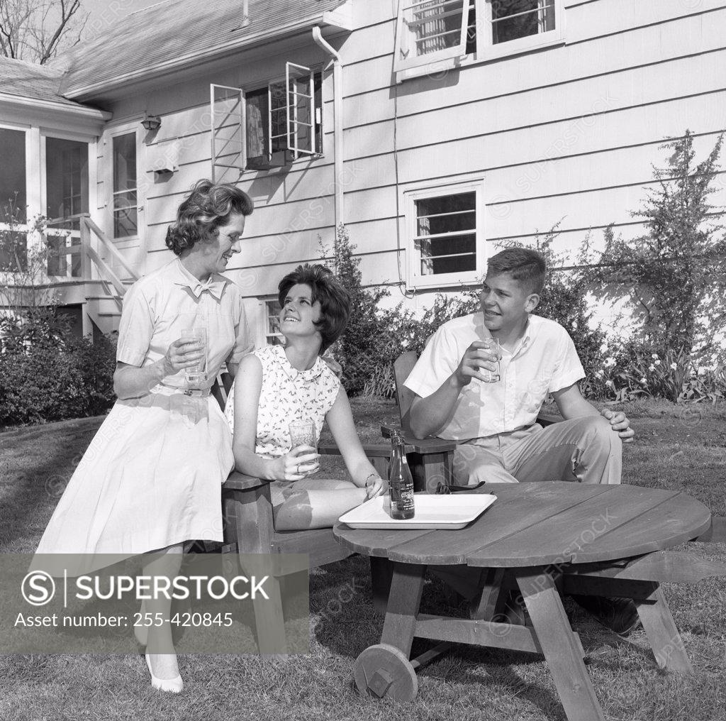 Stock Photo: 255-420845 Mature woman with adult son and daughter sitting in backyard and drinking water
