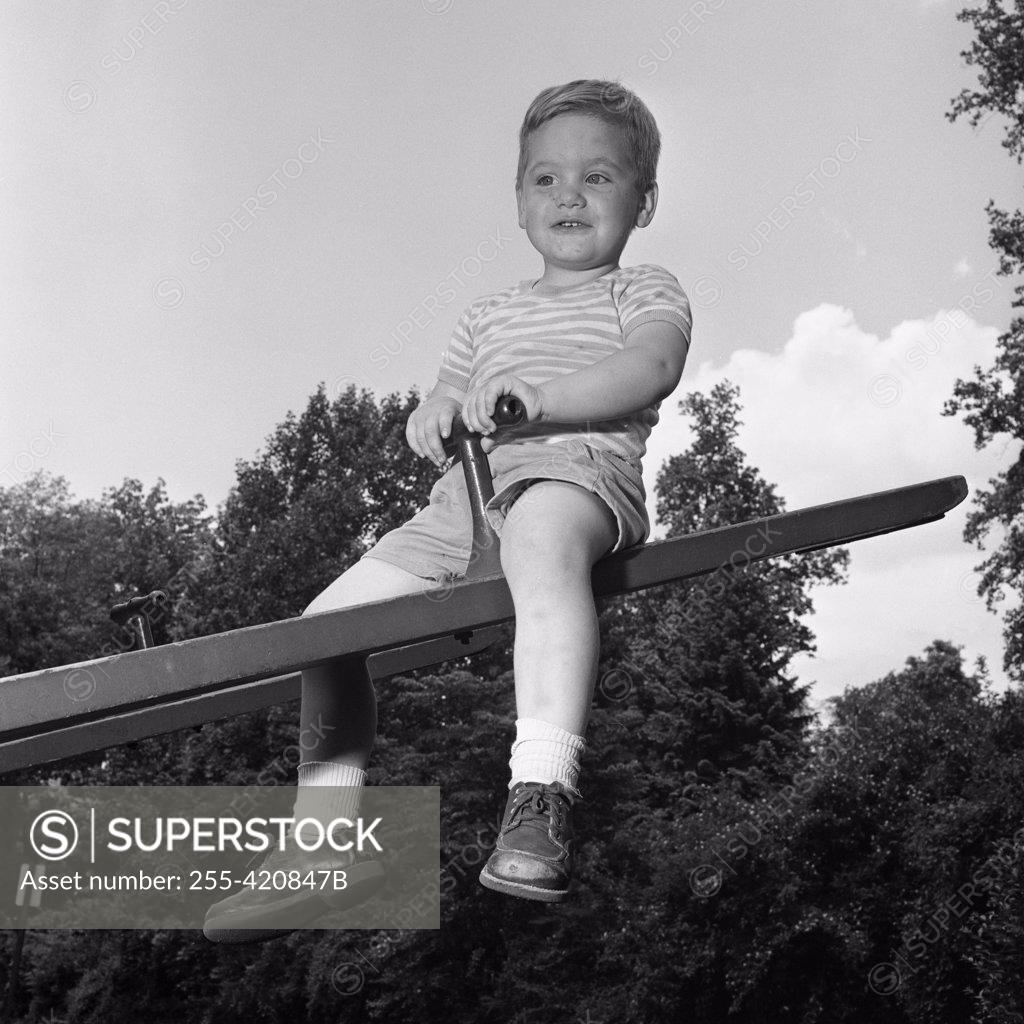 Stock Photo: 255-420847B Boy sitting on seesaw and smiling