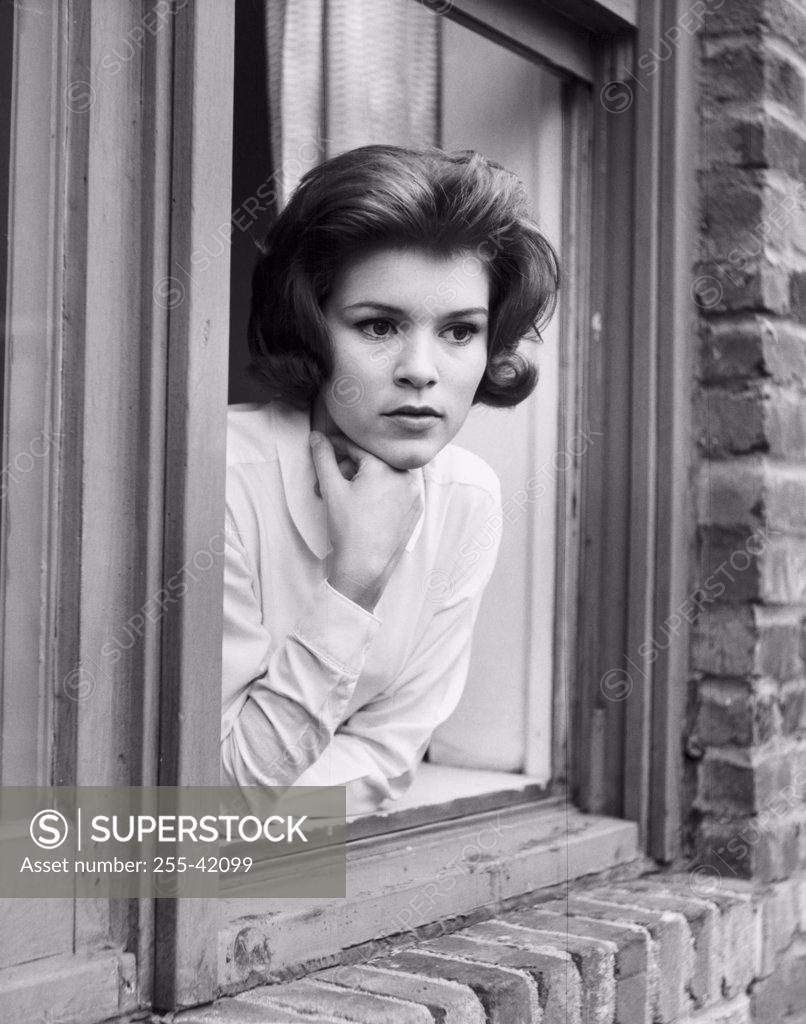 Stock Photo: 255-42099 Young woman leaning on window sill