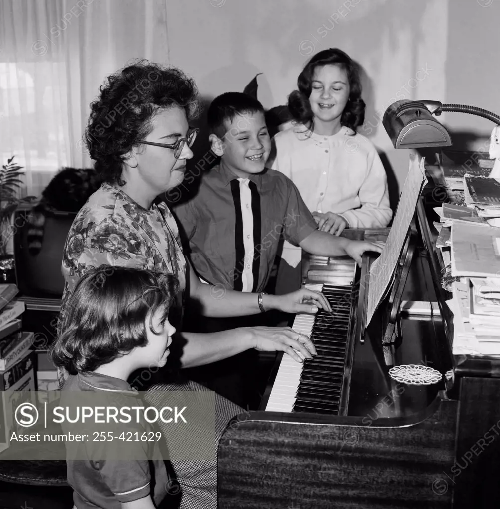 Mother playing piano and children singing