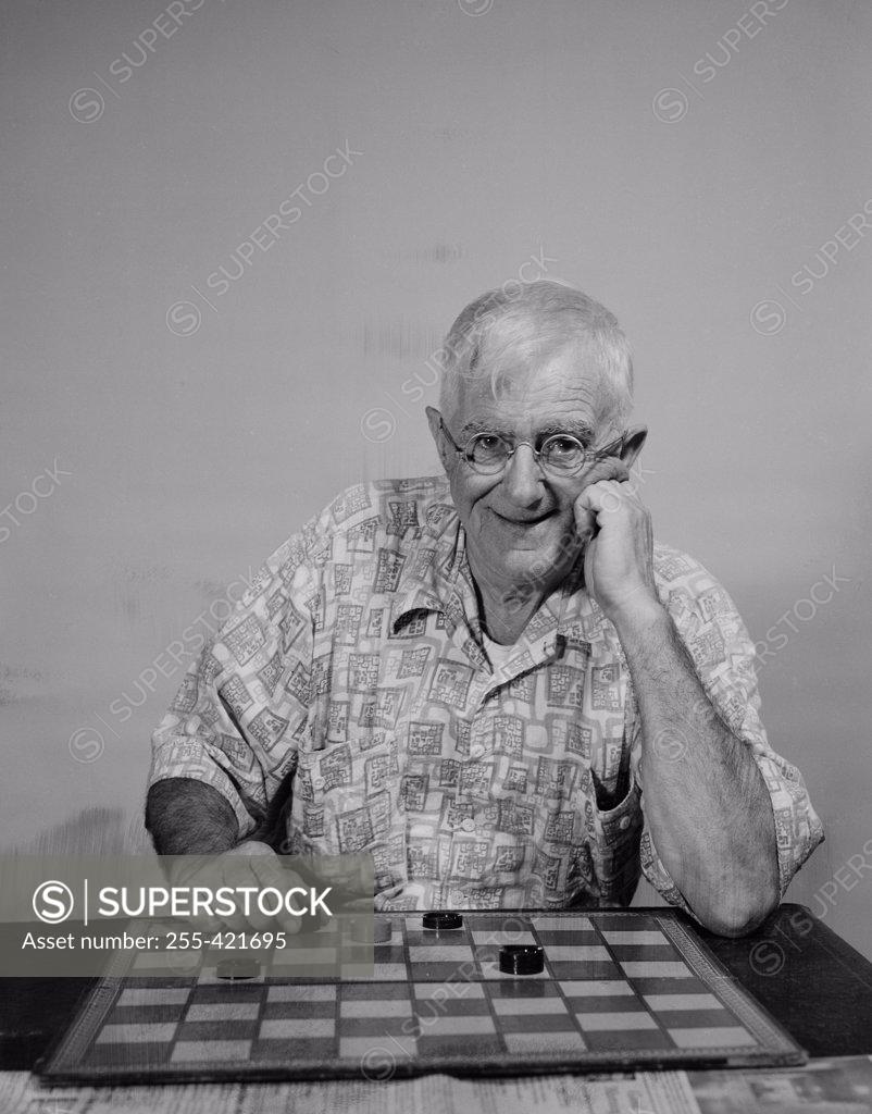 Stock Photo: 255-421695 Senior man with checkers looking at camera and smiling