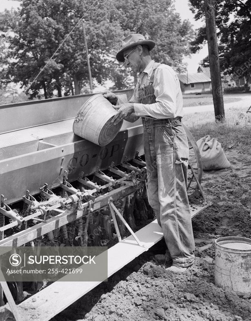Stock Photo: 255-421699 Mature man loading grinds into sowing machine