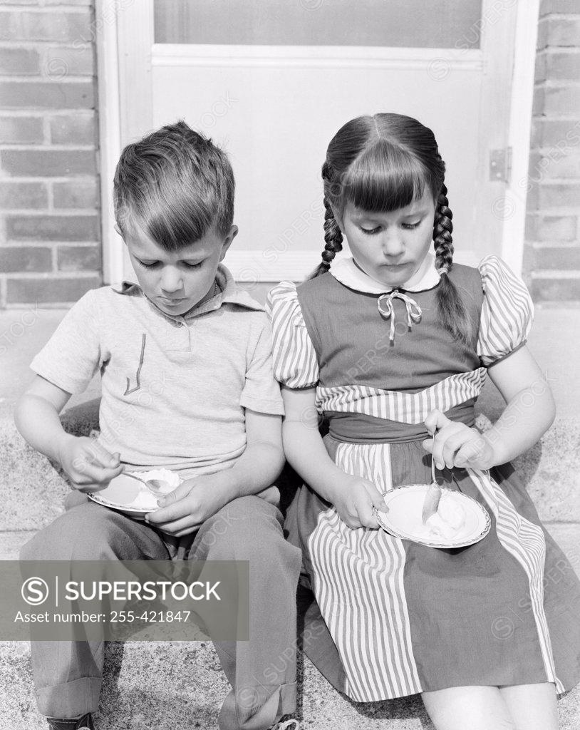 Stock Photo: 255-421847 Boy and girl eating ice cream on porch