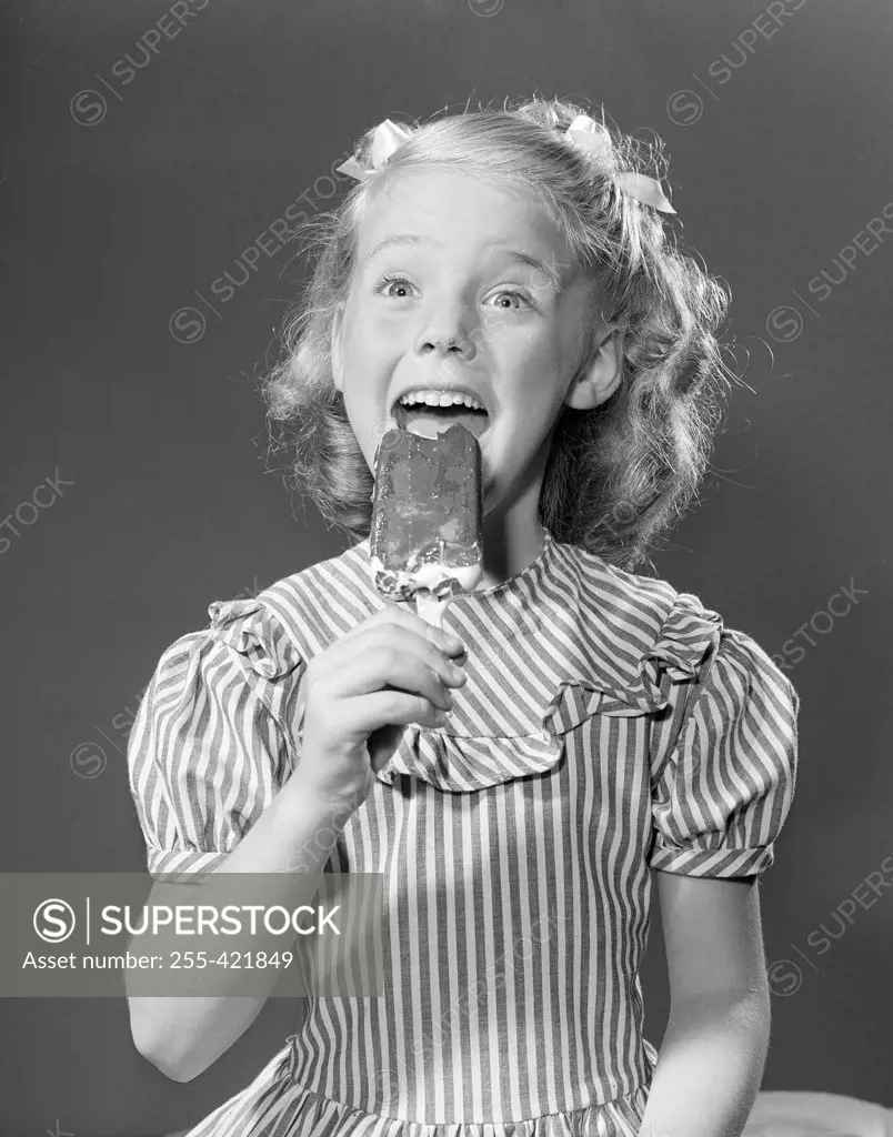 Studio portrait of girl eating popsicle