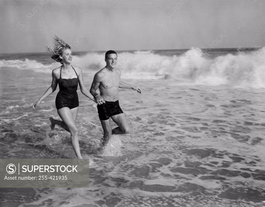 Stock Photo: 255-421935 Young couple running in sea